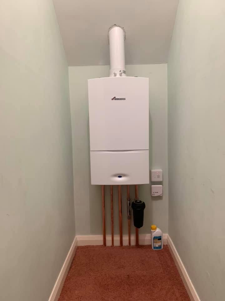 Boiler installation in a cupboard with copper pipework below